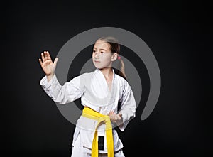 Child girl in karate suit with yellow belt show stance