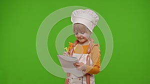 Child girl kid cook chef writing with pen in notebook new recipe standing over chroma key background