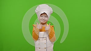 Child girl kid dressed as cook chef showing thumbs up, smiling, looking at camera on chroma key