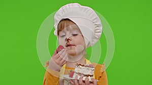 Child girl kid dressed as professional cook chef showing eating tasty handmade strawberry cake