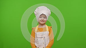 Child girl kid dressed as professional cook chef smiling, looking at camera on chroma key background