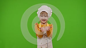 Child girl kid dressed as professional cook chef smiling, looking at camera on chroma key background