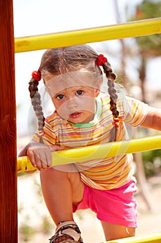 Child girl on ladder in playground.