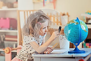 Child girl learning with globe at home