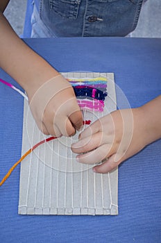 Child girl learning to use cardboard weaving loom