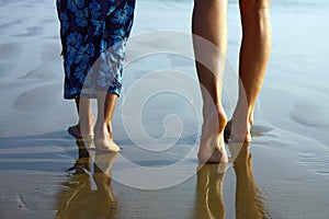 child and girl legs walking on the beach