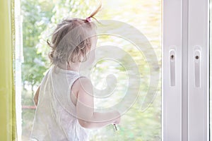 Child girl looking out window. Kid looks out window