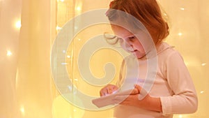 Child girl looking on the smartphone screen and playing in the downloaded application.