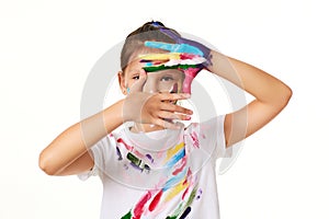 child girl looks through hands painted in colorful paint