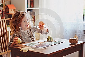 Child girl making herbarium at home, autumn seasonal crafts