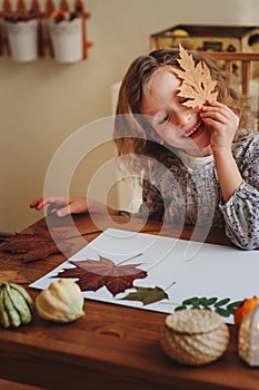 Child girl making herbarium at home, autumn seasonal crafts