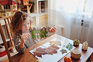 Child girl making herbarium at home, autumn seasonal crafts