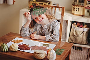 Child girl making herbarium at home, autumn seasonal crafts