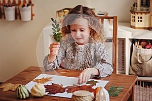 Child girl making herbarium at home, autumn seasonal crafts