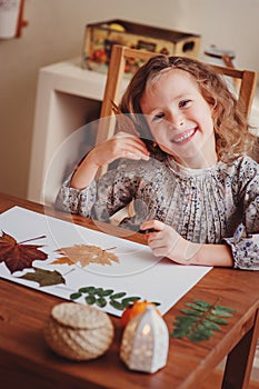 Child girl making herbarium at home, autumn seasonal crafts