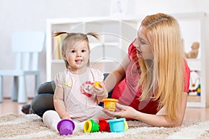 Child girl and mother playing together with toys