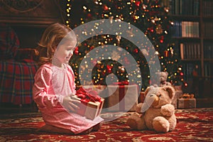 Child girl in nightgown with teddy bear in Christmas night