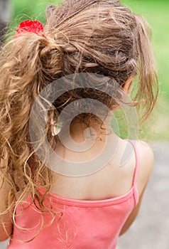 Child girl outside with long curly hair, back view