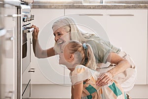 Child, girl or oven baking with grandparent, senior or elderly woman in kitchen, bonding house or family home. Happy