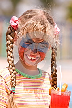 Child girl with paint on face drink juice.