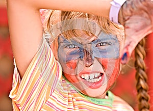 Child girl with paint on face in kids club.