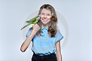 Child girl with pet green quaker parrot looking at camera on light studio background