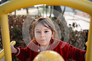 Child girl on the playground climbing structures, outdoors free play of primary school