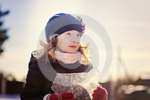 Child girl playing with block of ice on winter walk