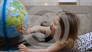 Child girl playing with globe. Baby studies geography and a map of the world
