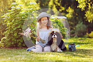 child girl playing with her spaniel dog in summer garden