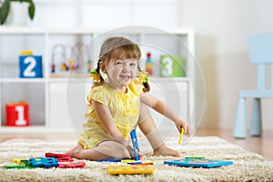 Child girl playing indoors with sorter toy sitting on soft carpet photo