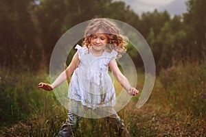 Child girl playing with leaves in summer forest. Nature exploration with kids