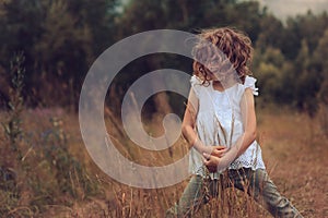 Child girl playing with leaves in summer forest. Nature exploration with kids