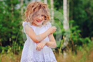 Child girl playing with leaves in summer forest. Nature exploration with kids