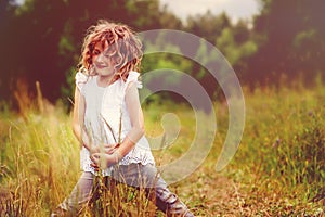 Child girl playing with leaves in summer forest. Nature exploration with kids