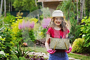 Child girl playing little gardener and helping in summer garden