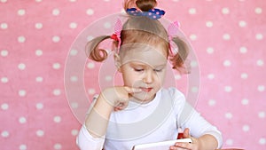 Child girl playing with a mobile phone. Baby uses a game application on the smartphone.