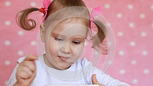 Child girl playing with a mobile phone. Baby uses a game application on the smartphone. Potrait closeup