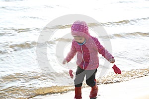 Child girl playing by the sea in autumn