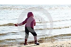 Child girl playing by the sea in autumn