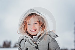 Child girl playing with snow on the walk in winter forest