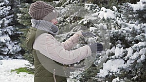 child girl playing with snow in the winter forest  then she will prick herself with a branch