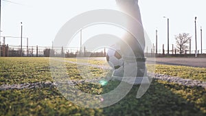 A child girl playing with soccer ball under sun light. Green field in city park at sunny day. Action sport outdoors of