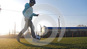 A child girl playing with soccer ball under sun light. Green field in city park at sunny day. Action sport outdoors of