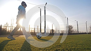 A child girl playing with soccer ball under sun light. Green field in city park at sunny day. Action sport outdoors of