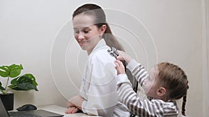 Child, girl plays with doctor and listens to him with stethoscope. Caring professional woman pediatrician playing with