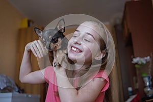 Child girl plays with little dog black hairy chihuahua doggy