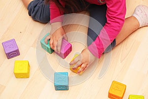 Child girl plays with toys at home, in kindergarten or nursery. Little girl plays with colored cubes at home