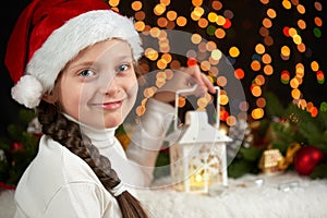 Child girl portrait with christmas decoration, dark background with lights, face expression and happy emotions, dressed in santa h