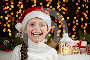 Child girl portrait in santa hat with christmas decoration, dark background with lights, face expression and happy emotions, winte